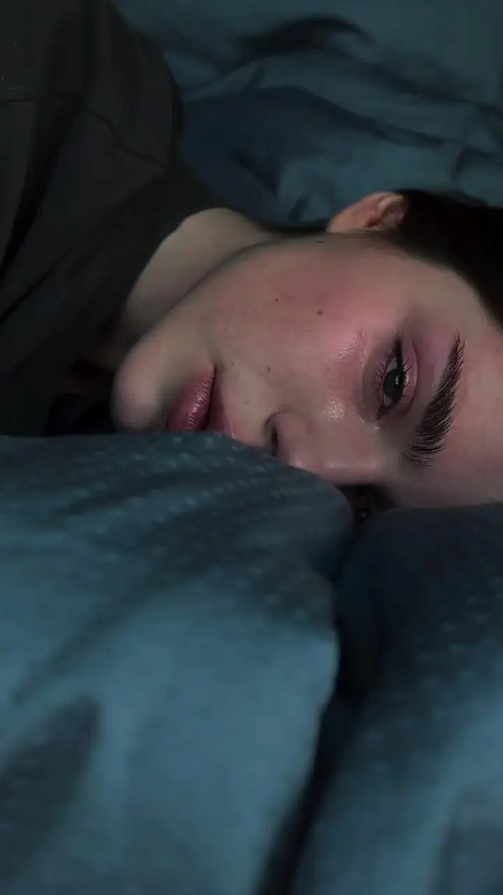 A person lying awake at night, looking at a phone