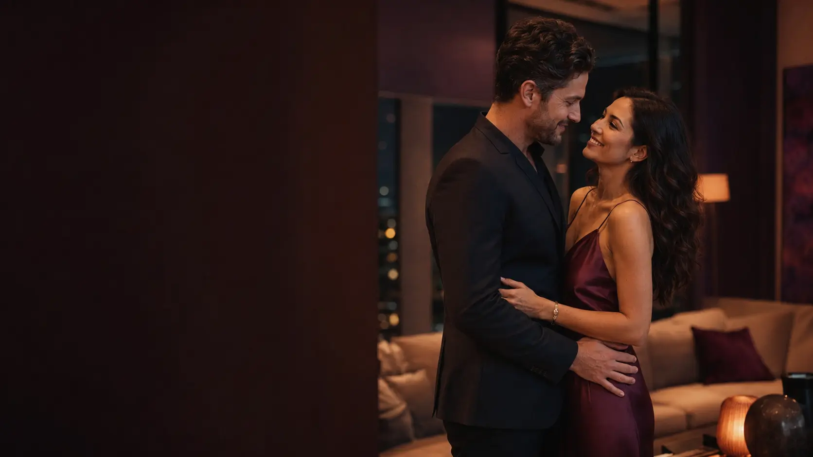 A couple sharing a warm, private moment in a softly lit living room at night.